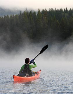 Kayaker on a misty lake.