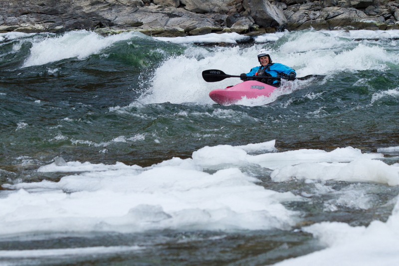 Kayaker on wave in icy water.